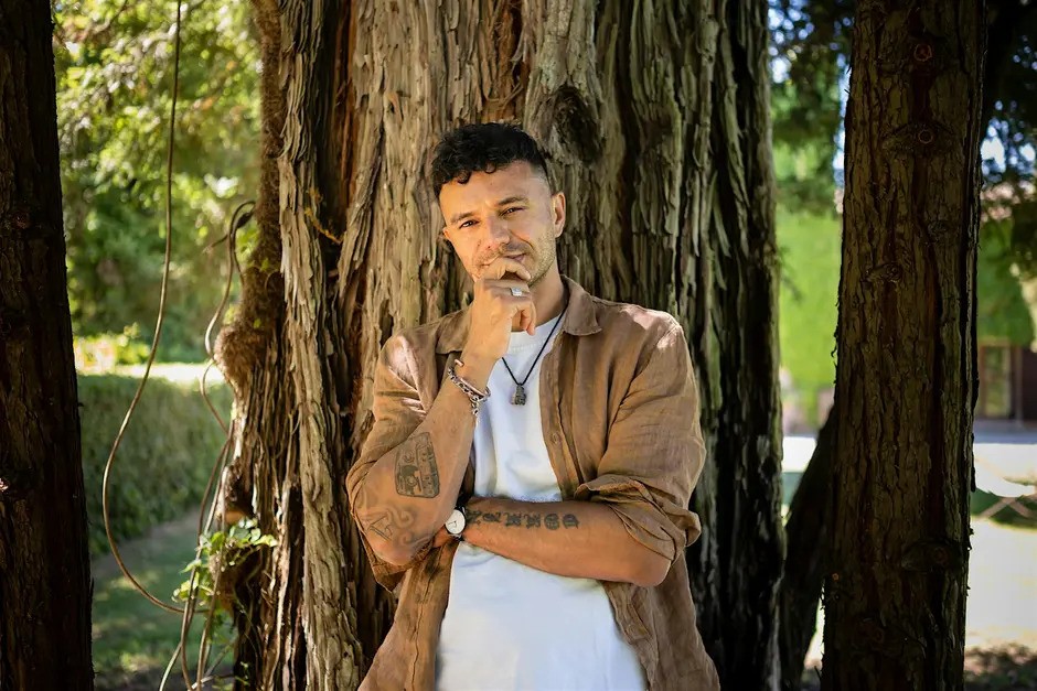 A man leaning against a tree